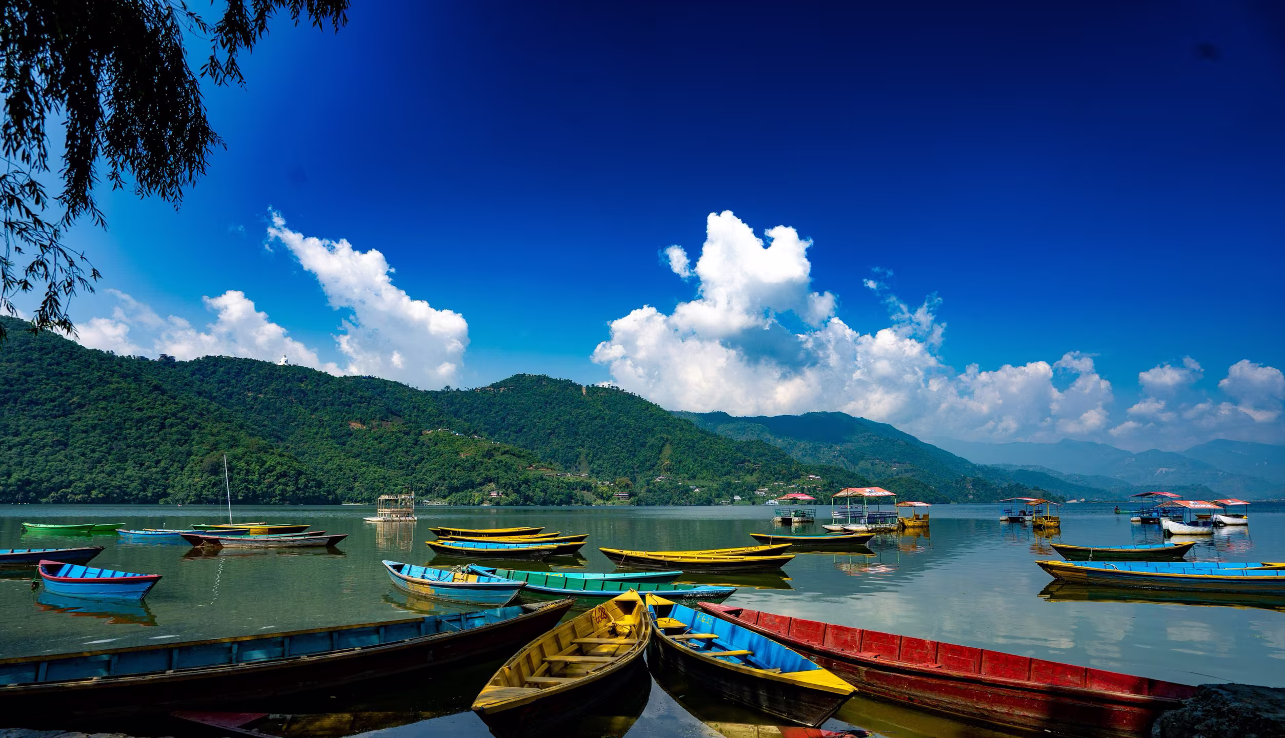 Boats on the lake with green hills rising behind