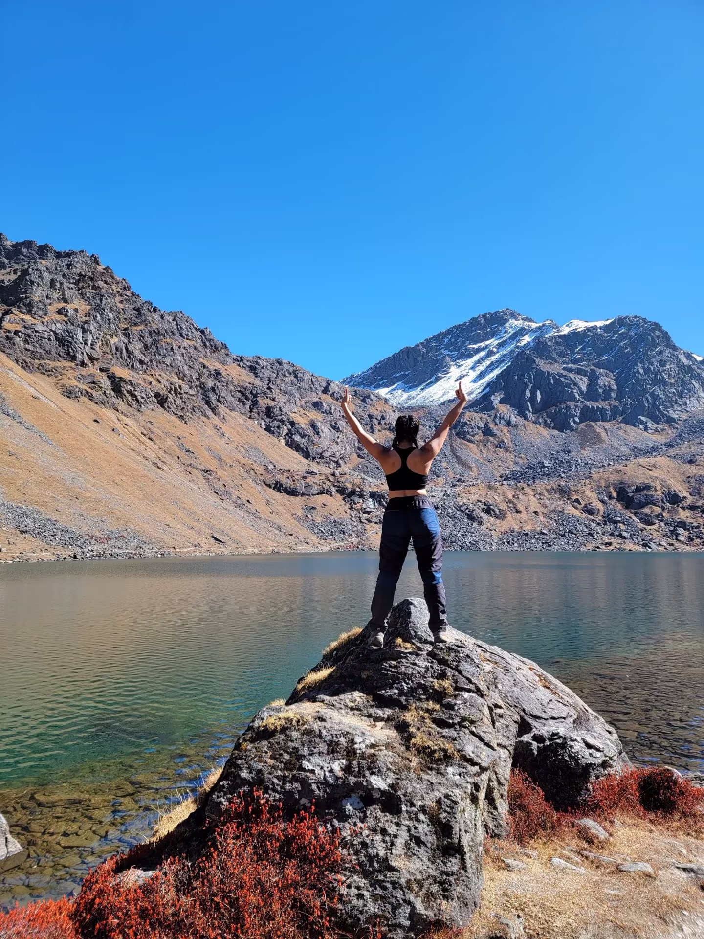 A trekker standing at the shore of Gosaikunda lake