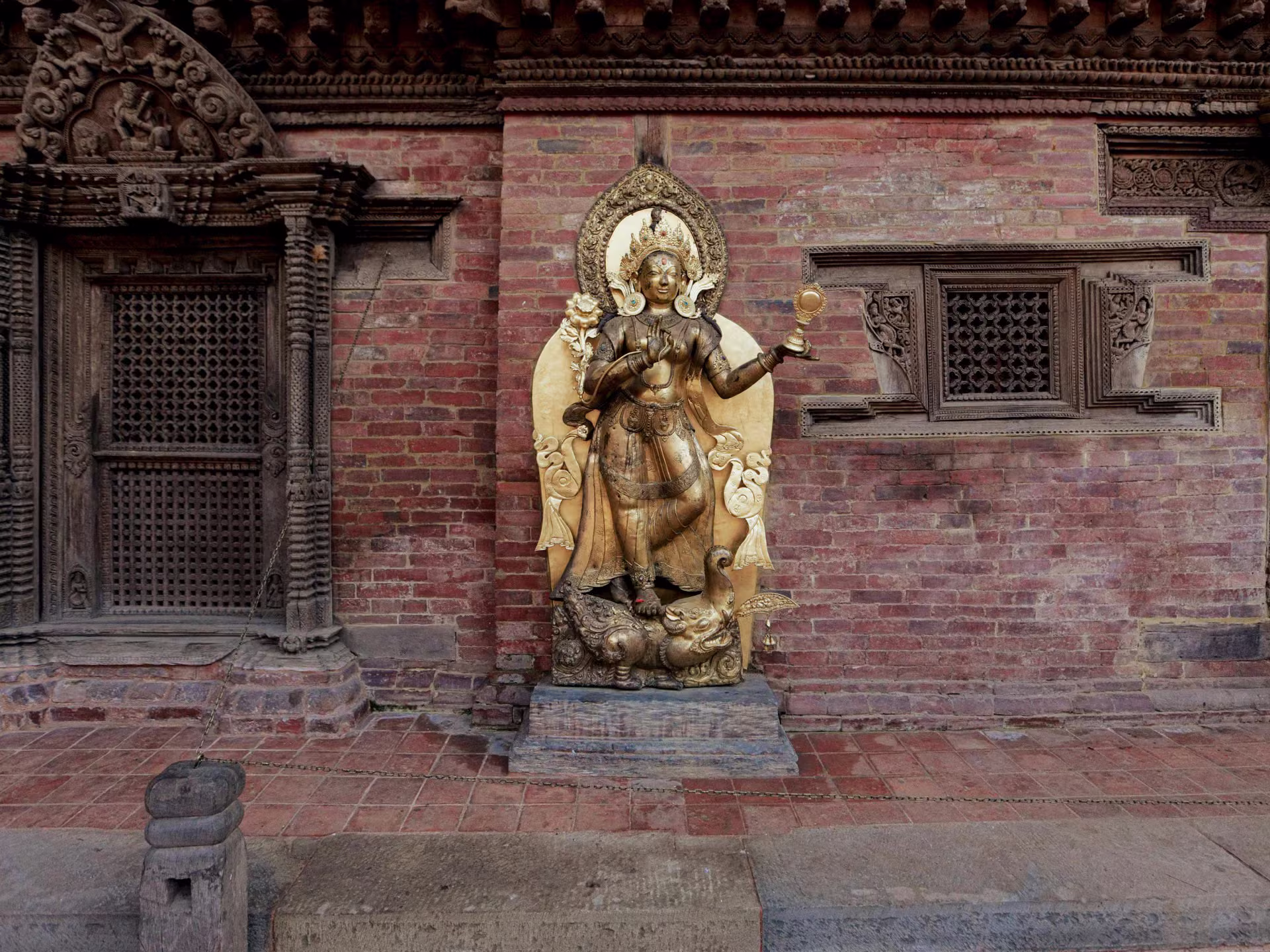 A golden statue against an old brick wall