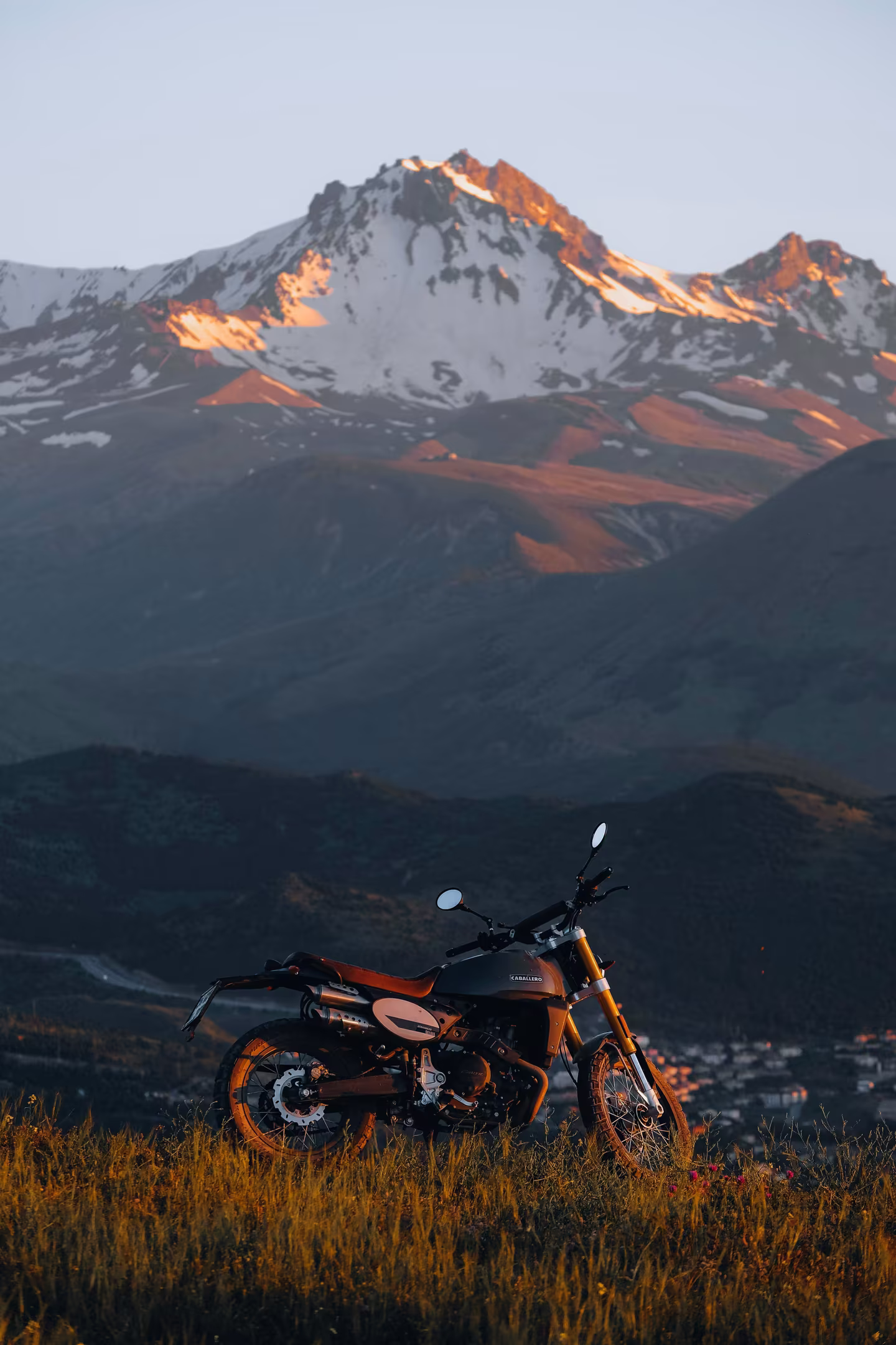 A motorcycle parked before snow-capped Himalayan peaks at sunrise