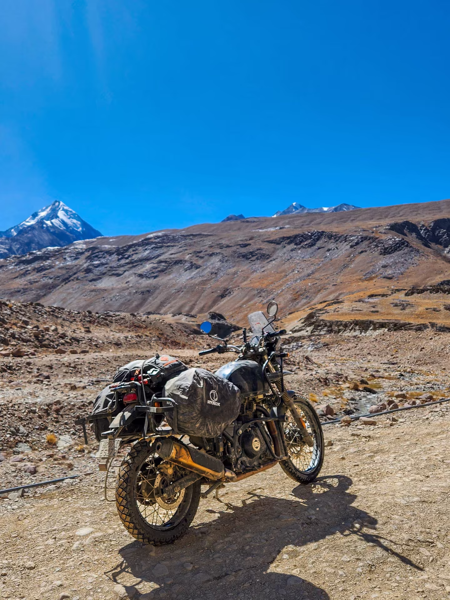 A motorcycle loaded with expedition luggage on a high mountain road