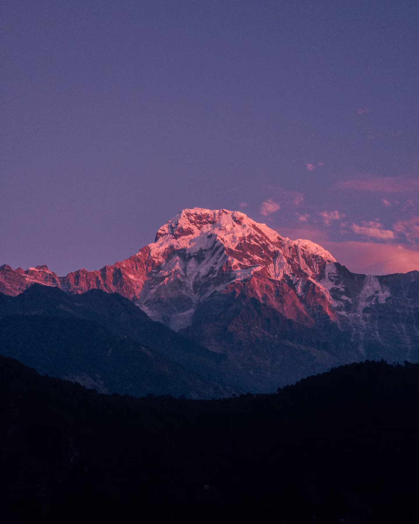 A snowy peak tinted red by the last rays of sunset