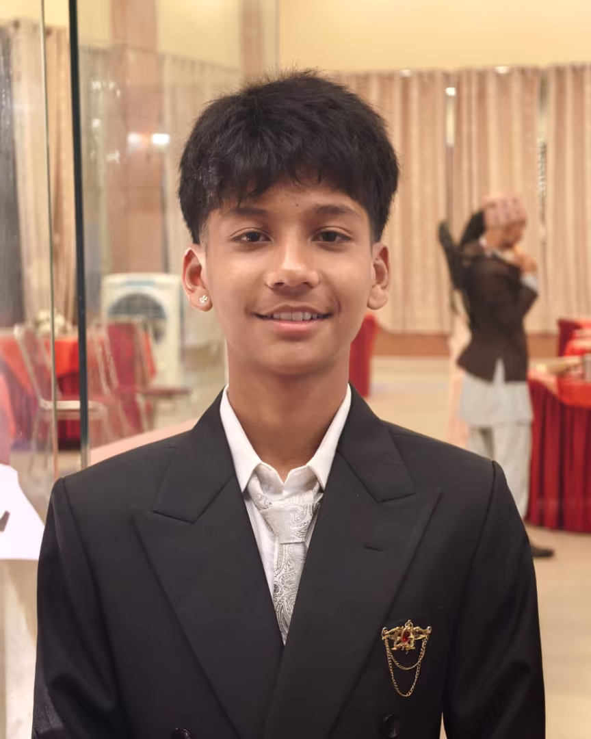 Rijan Poudel in a black suit and white tie, smiling at a formal event