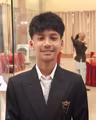 Rijan Poudel in a black suit and white tie, smiling at a formal event