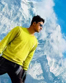 Rohan KC in a bright base layer on a high ridge, looking out toward a snow-capped Himalayan peak