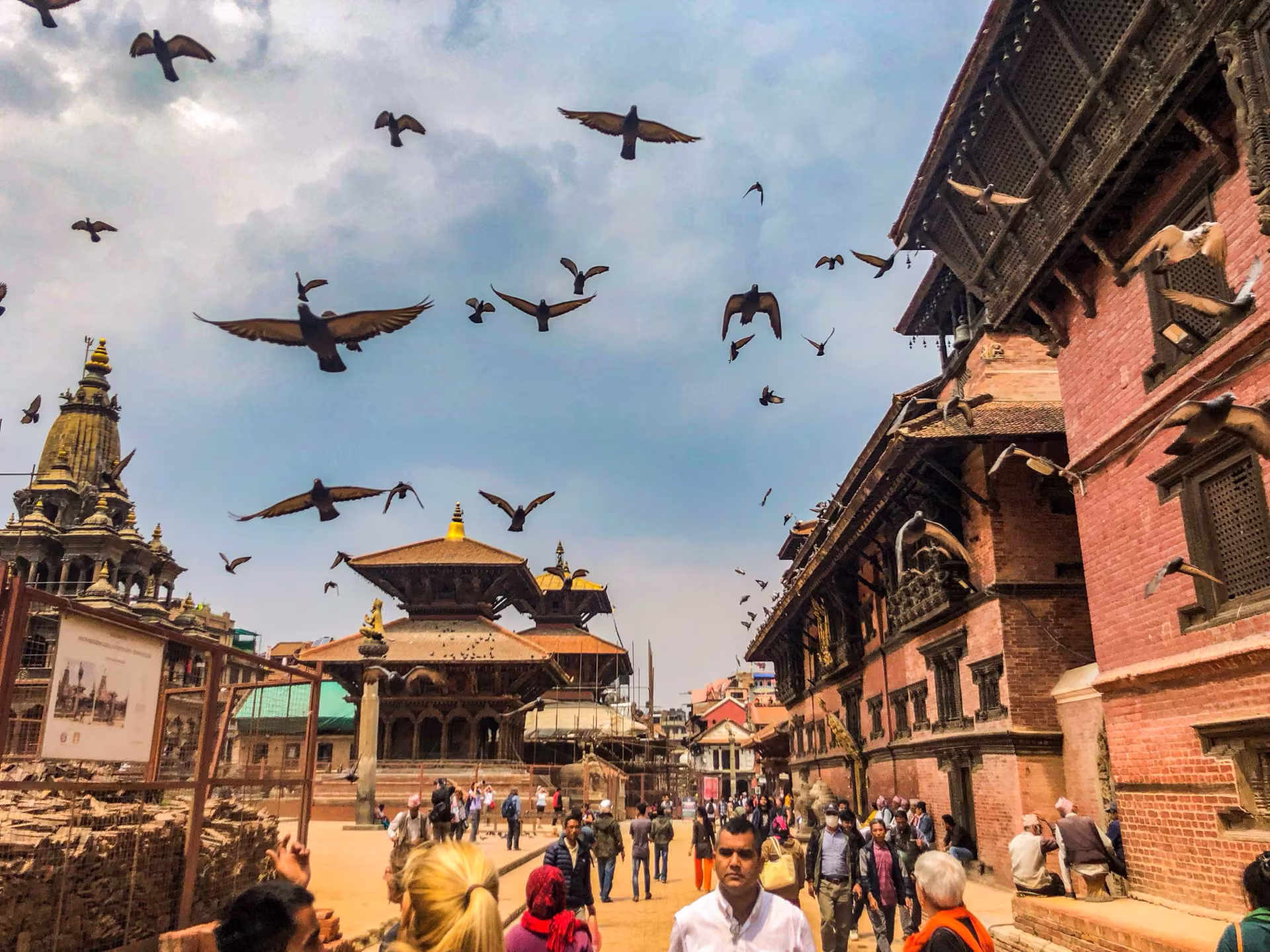 A busy temple square with pigeons taking flight