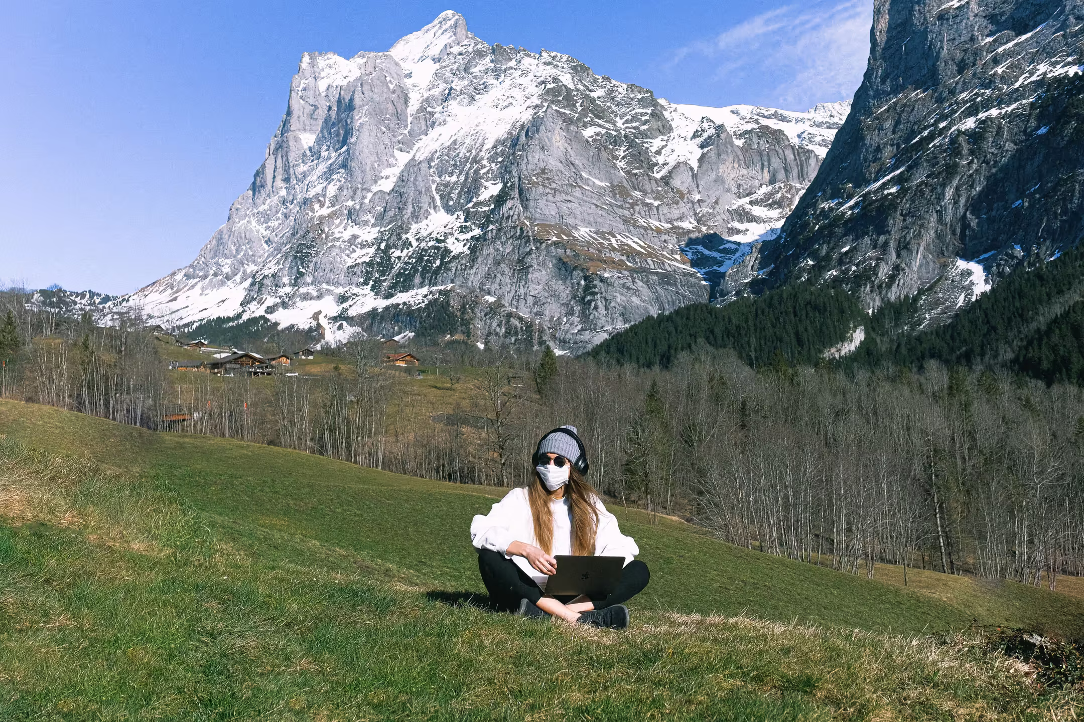 Person working on a laptop in the hills with Himalayan mountain views in the background