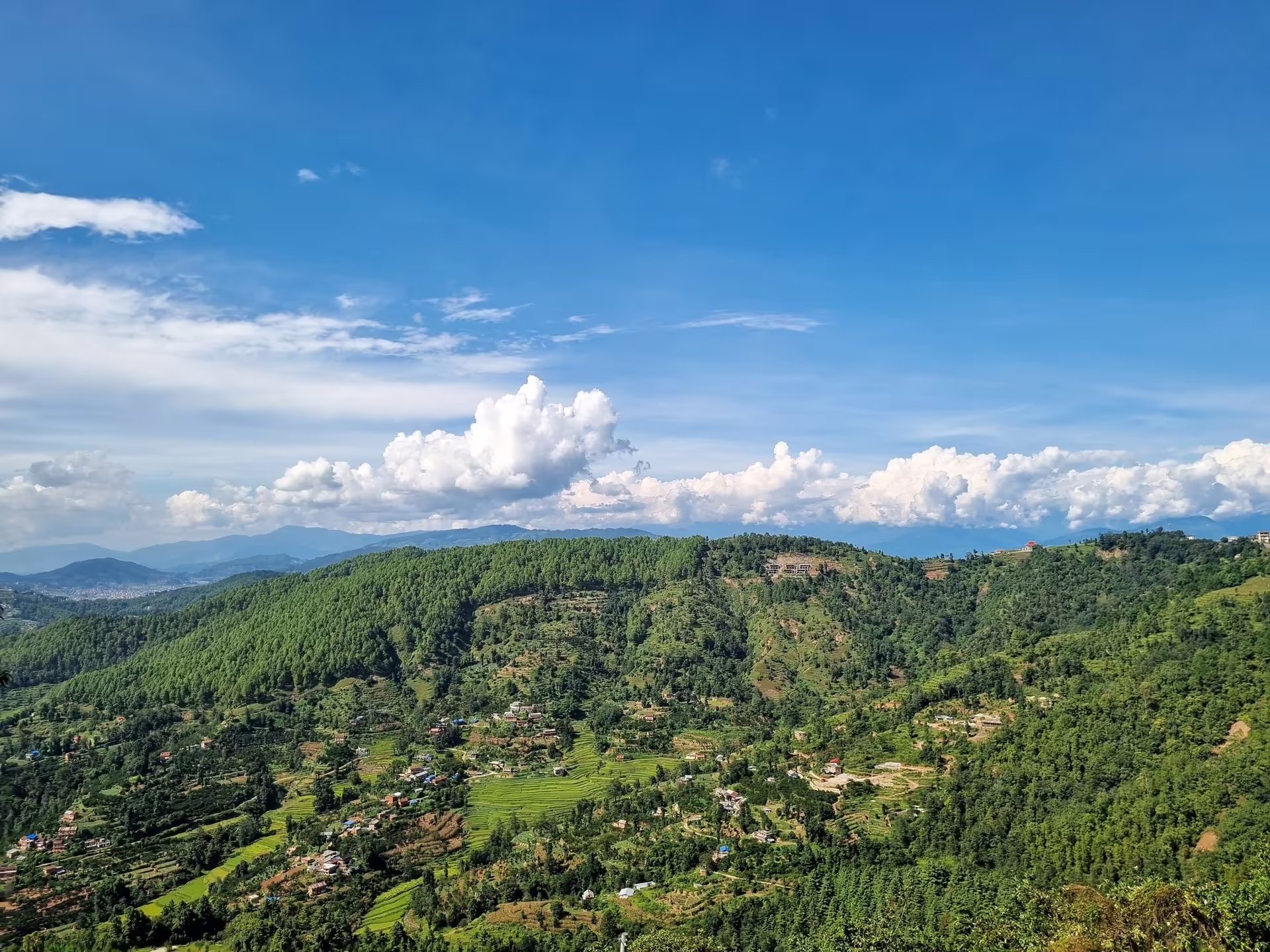 Lush green Nepali landscape with village homes nestled in monsoon hills
