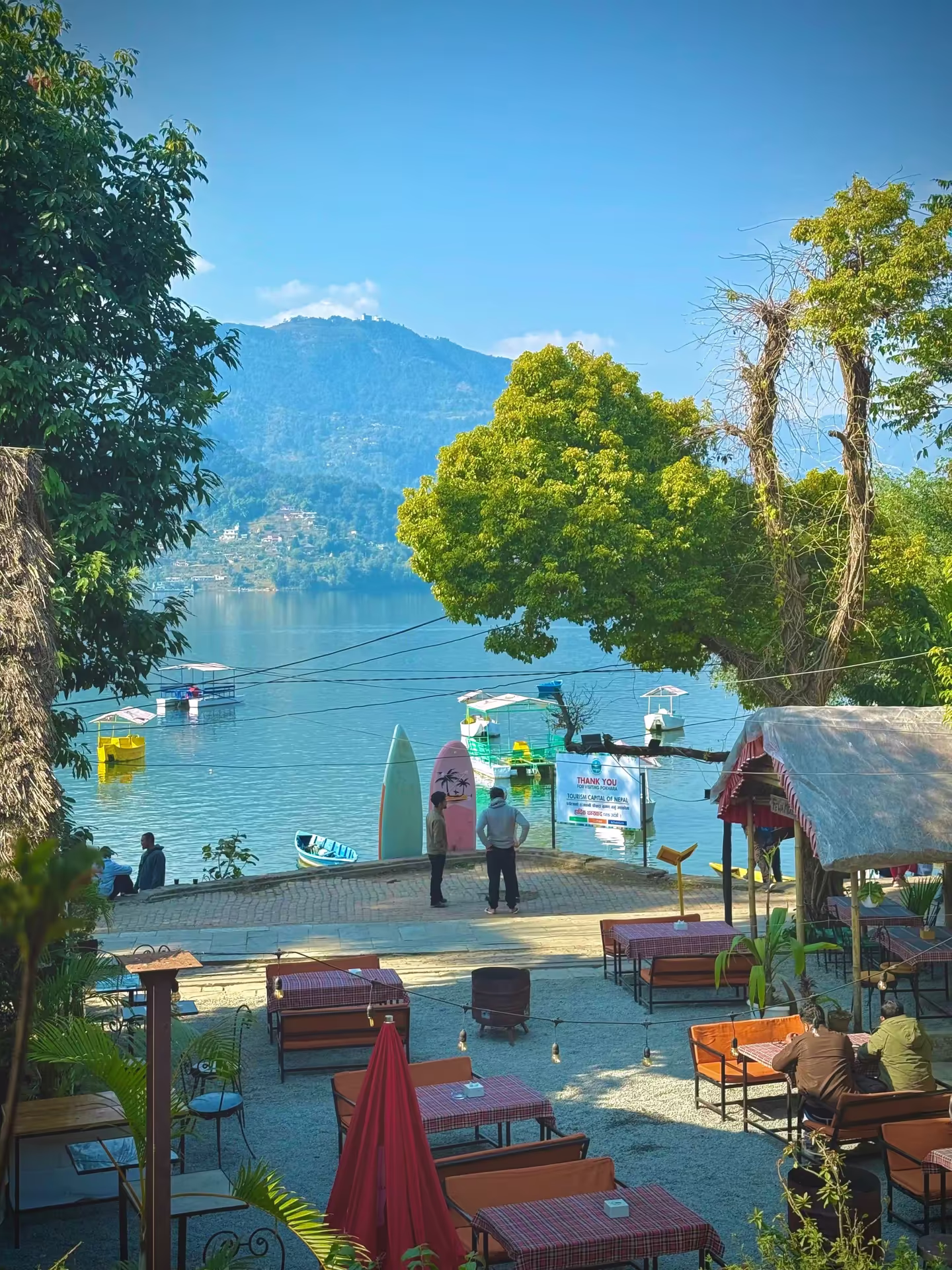 Families boating on Phewa Lake in Pokhara with green hills in the background
