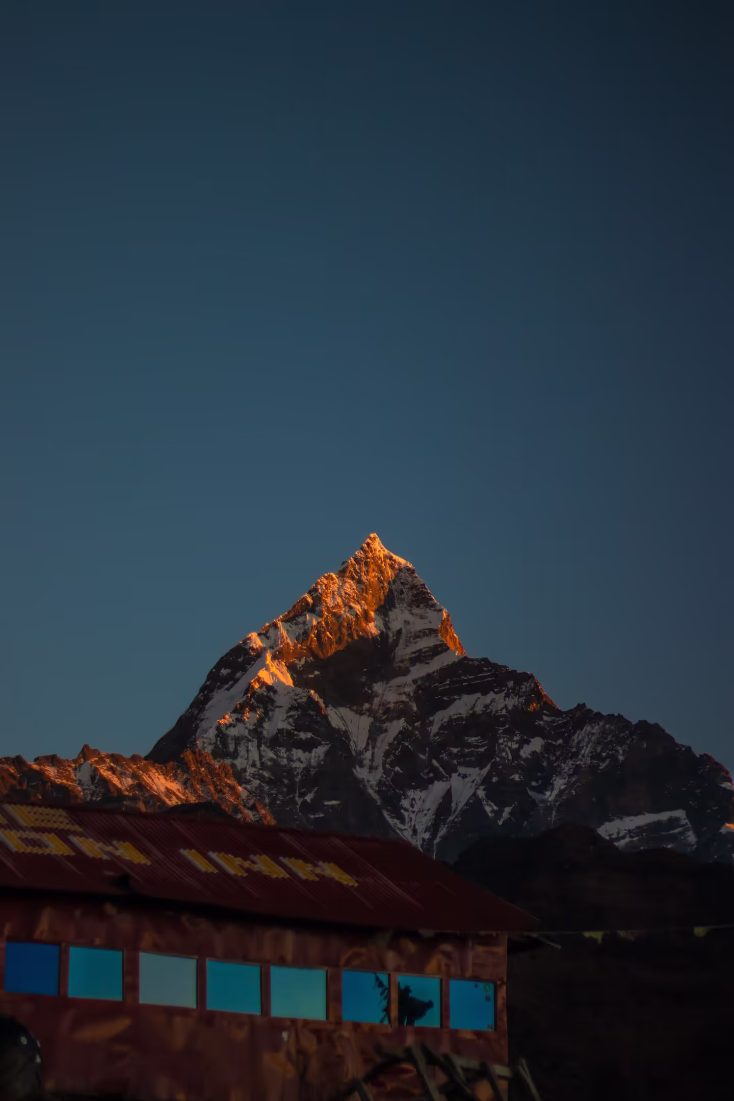 A teahouse on the trekking trail with a dramatic snow-covered mountain backdrop