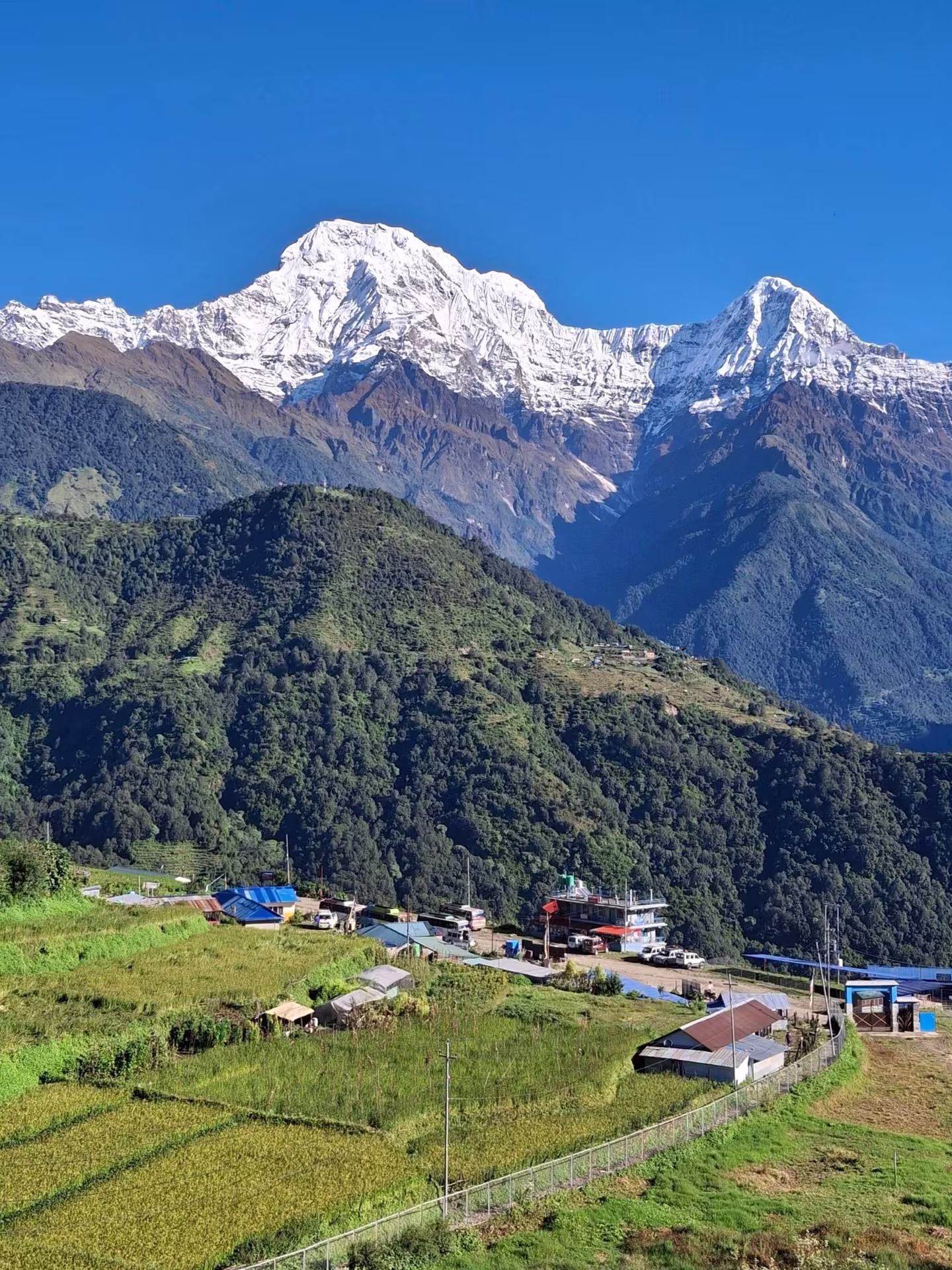 A traditional Nepali hill village with mountains visible in the background, similar to the setting of Bandipur